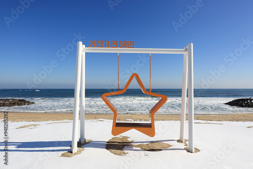 Geojin Beach, Goseong-gun, Gangwon-do, South Korea - January 21, 2022: Winter view of snow covered beach with star swing against wave on the sea photo