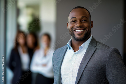 Smiling African American business man standing in front of his team.