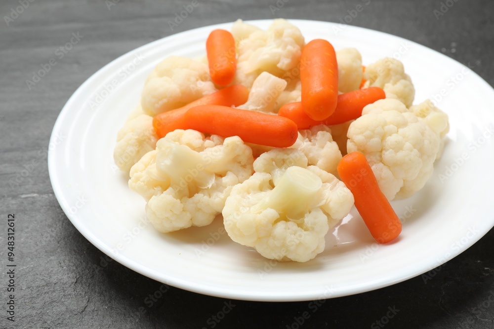 Tasty cauliflower with baby carrots on black table, closeup Tasty cauliflower with baby carrots on black table, closeup