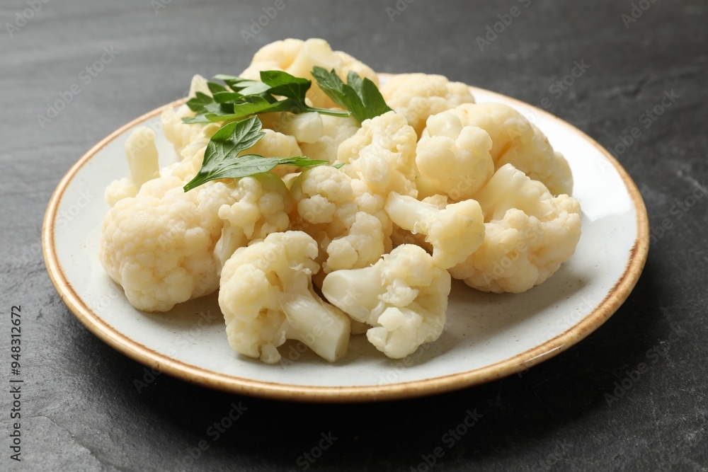 Tasty cauliflower with parsley on black table, closeup Tasty cauliflower with parsley on black table, closeup