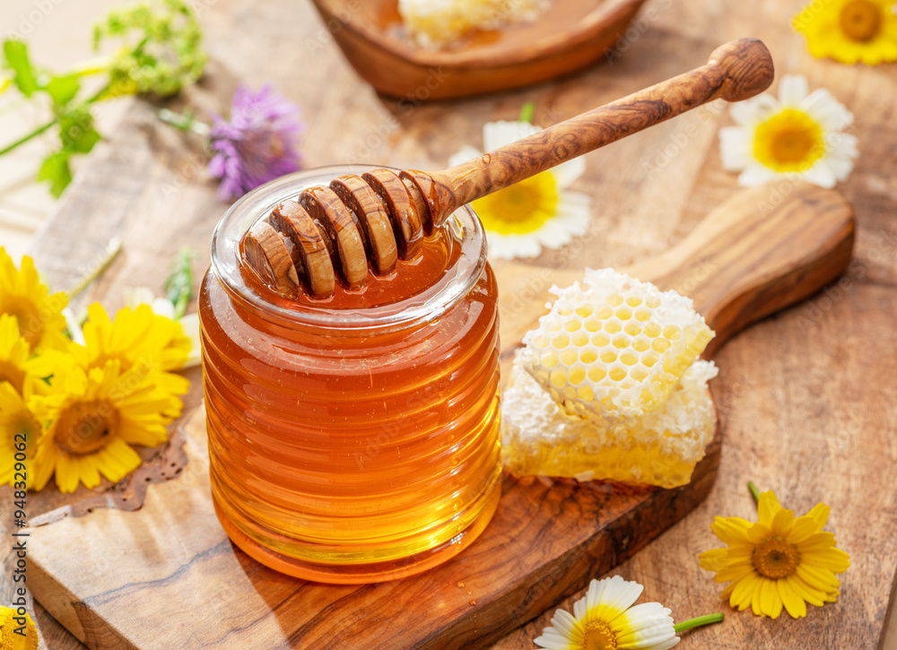 Natural organic honey in glass jar, honey dipper and honeycombs are near. Natural food background. Natural organic honey in glass jar, honey dipper and honeycombs are near. Natural food background.