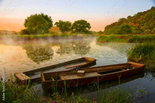 Changnyeong-gun, Gyeongsangnam-do, South Korea - May 1, 2000: Summer and sunrise view of foggy Upo Wetland with a ferry boat and sea plant on water photo