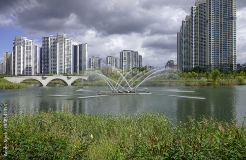 Cheongna International City, Seo-gu, Incheon, South Korea - September 22, 2021: Summer view of fountain water at Cheongna Lake Park with the background of high-rise apartments photo