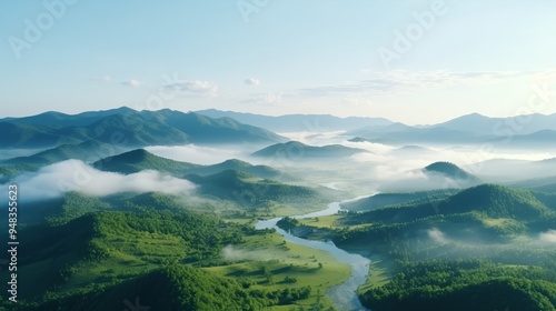 Aerial view of lush valleys and winding river under a clear blue sky at dawn, surrounded by misty mountains