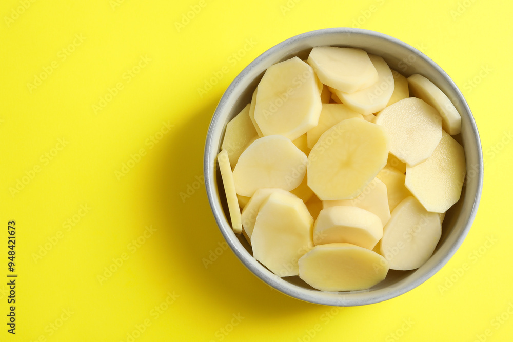 Cut fresh raw potatoes in bowl on yellow background, top view. Space for text Cut fresh raw potatoes in bowl on yellow background, top view. Space for text
