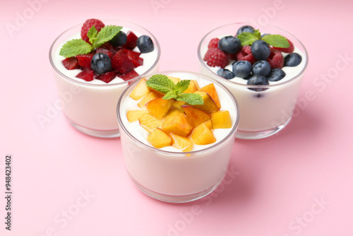 Tasty yogurt with fresh berries, fruits and mint in glasses on pink background, closeup