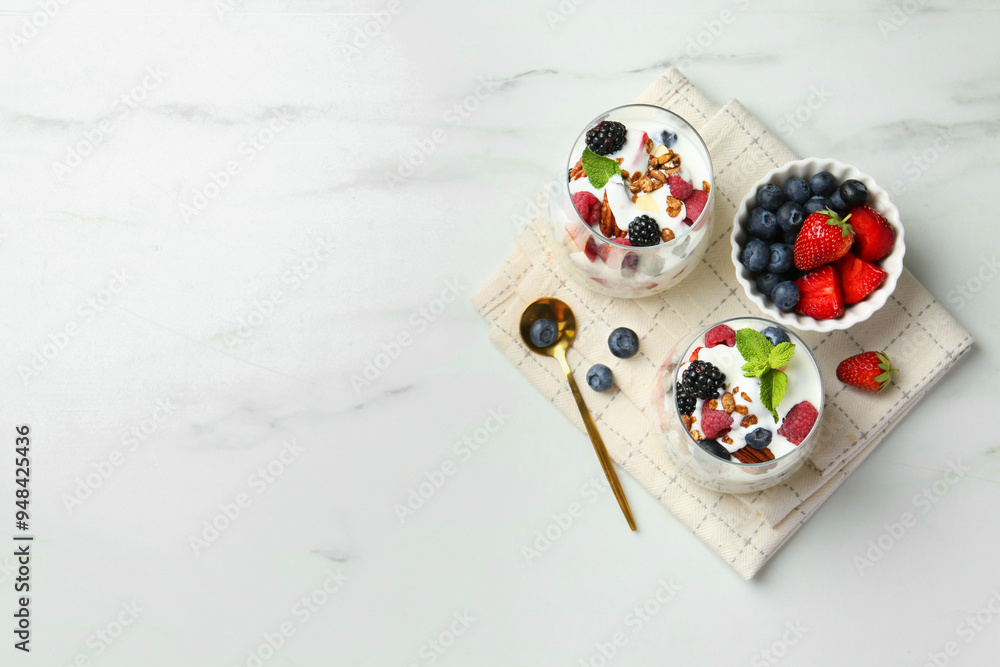 Tasty yogurt with fresh berries, granola and mint in glasses served on white table, flat lay. Space for text Tasty yogurt with fresh berries, granola and mint in glasses served on white table, flat lay. Space for text