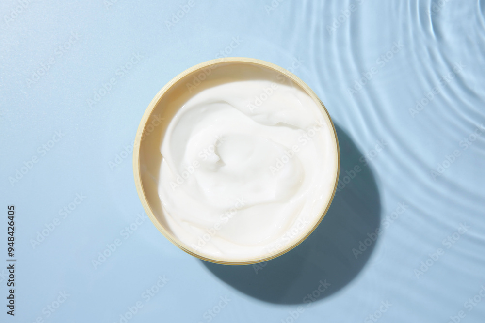 Cosmetic product. Jar with cream in water on light blue background, top view Cosmetic product. Jar with cream in water on light blue background, top view
