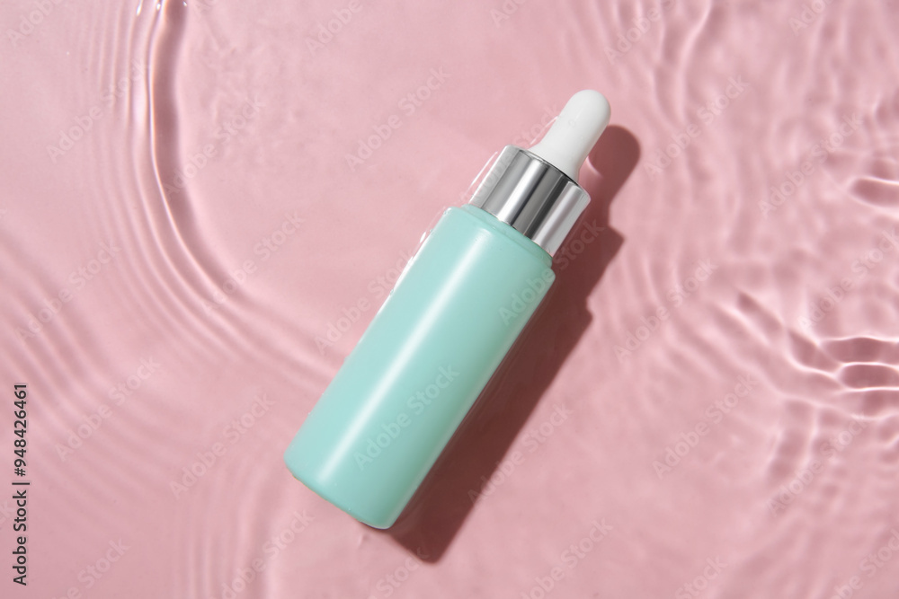 Bottle of cosmetic product in water on pink background, top view Bottle of cosmetic product in water on pink background, top view