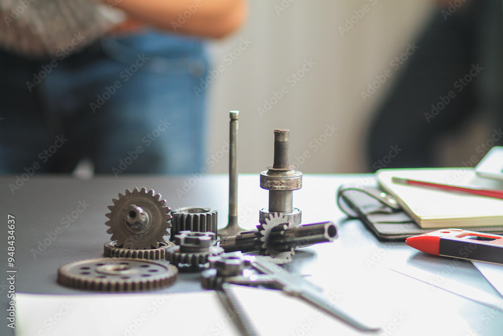 The gear set is placed on the workbench of a team of factory mechanical engineers to study and design the working system of the mechanical gearbox in the factory to complete the production. The gear set is placed on the workbench of a team of factory mechanical engineers to study and design the working system of the mechanical gearbox in the factory to complete the production.