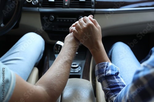 Lovely couple holding hands together while traveling by car, closeup photo