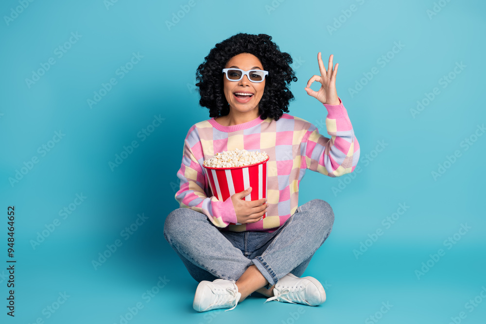 Full body photo of attractive young woman watch movie okay dressed stylish pink plaid clothes isolated on blue color background Full body photo of attractive young woman watch movie okay dressed stylish pink plaid clothes isolated on blue color background