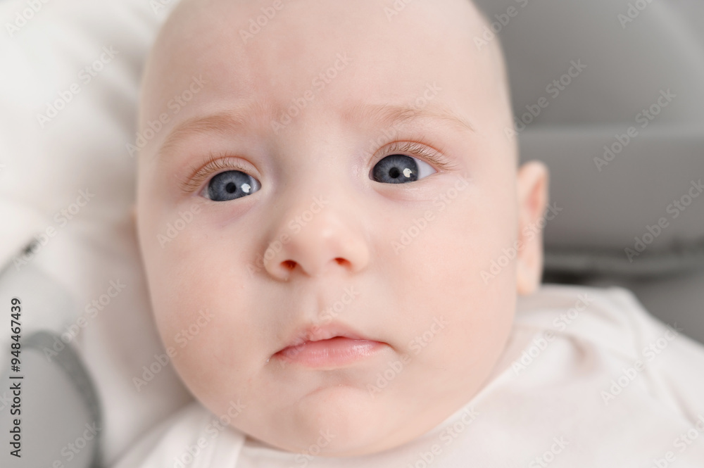 Cute little newborn baby lies comfortably on baby chair,looking curiously straight into camera,close-up. Concept of infancy, baby products and baby services, child care, motherhood, maternity leave. Cute little newborn baby lies comfortably on baby chair,looking curiously straight into camera,close-up. Concept of infancy, baby products and baby services, child care, motherhood, maternity leave.