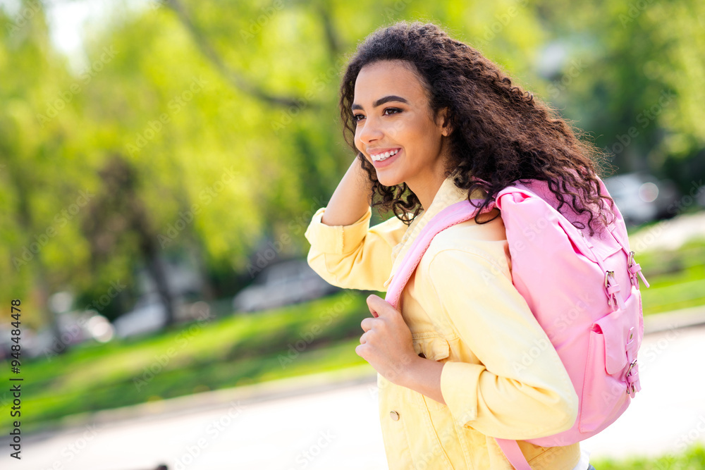 Portrait of positive adorable cheerful woman touch wavy hair pink backpack wear yellow jacket walking park sunny spring weather outside Portrait of positive adorable cheerful woman touch wavy hair pink backpack wear yellow jacket walking park sunny spring weather outside