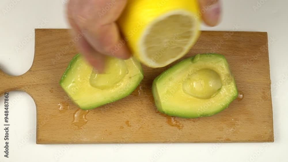 Person put a little lemon juice on the open side of cut avocado to slow down its oxidation Person put a little lemon juice on the open side of cut avocado to slow down its oxidation