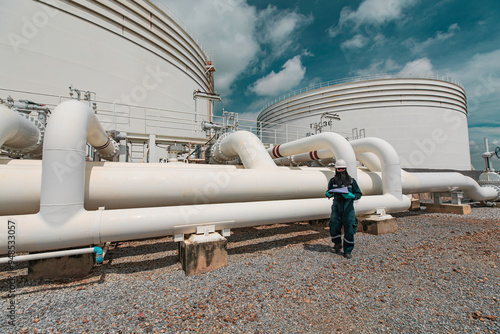 Male worker inspection at steel long pipes and pipe elbow in station oil factory during refinery valve of visual check record pipeline tank oil and gas photo