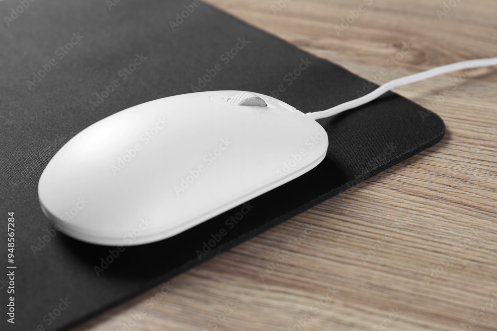 White computer mouse and black mousepad on wooden table, closeup White computer mouse and black mousepad on wooden table, closeup