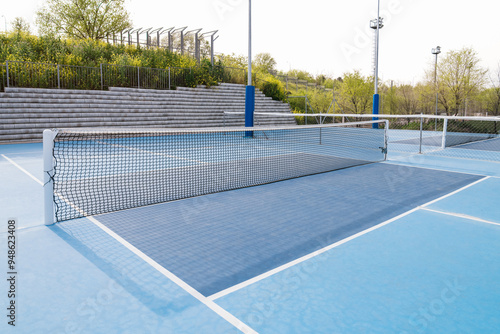 Wallpaper Mural Close-up of a pickleball net on an outdoor court with blue flooring and lush surroundings. Torontodigital.ca