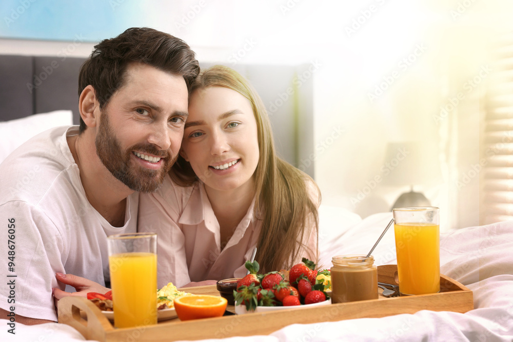 Happy couple having breakfast in bed on sunny morning. Space for text Happy couple having breakfast in bed on sunny morning. Space for text