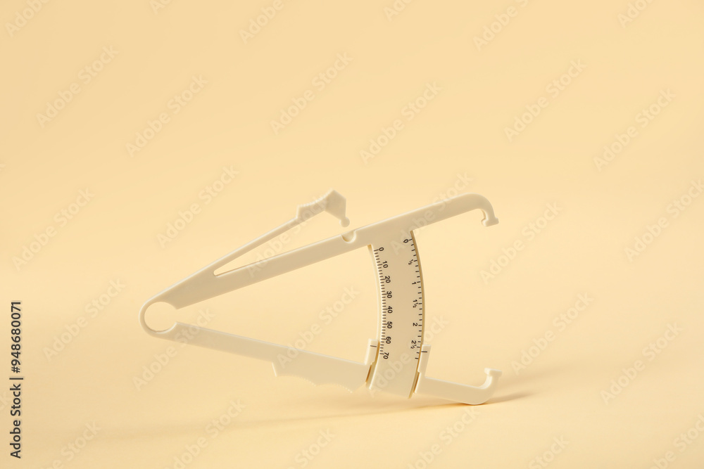 Obraz premium Plastic body fat caliper on beige background