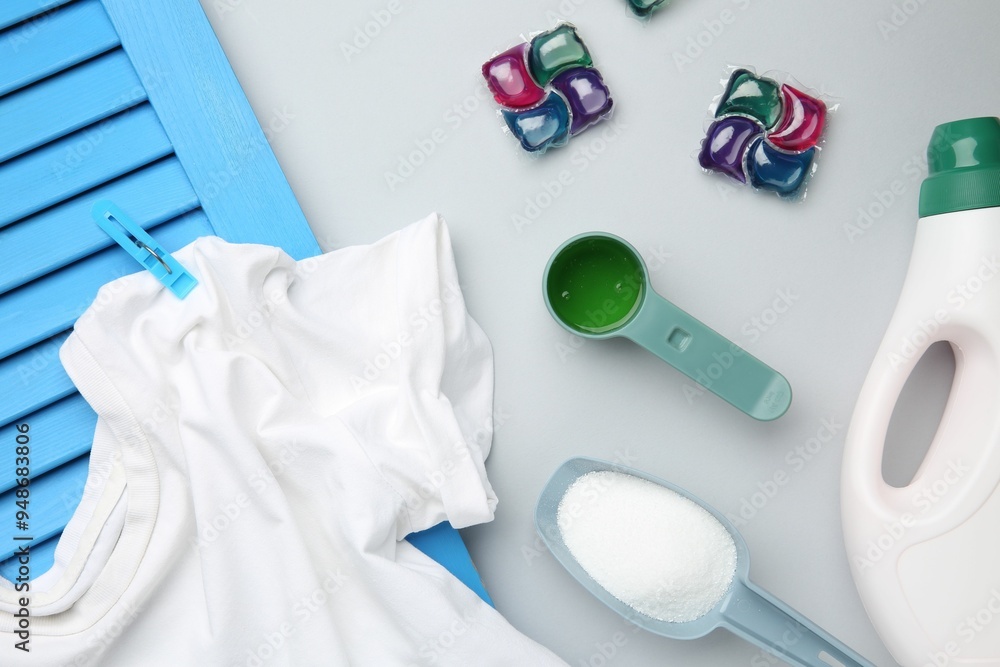 Different laundry detergents and t-shirt on grey background, flat lay Different laundry detergents and t-shirt on grey background, flat lay