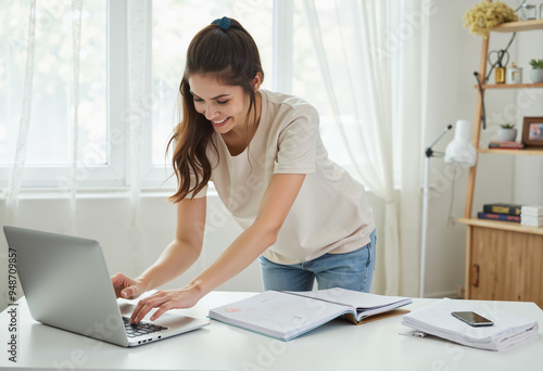 Smiling woman using a laptop at home office desk