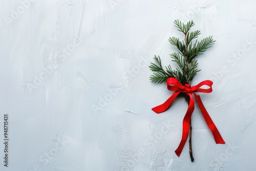 Minimalist Christmas background with a single pine branch and a red bow on a white backdrop photo