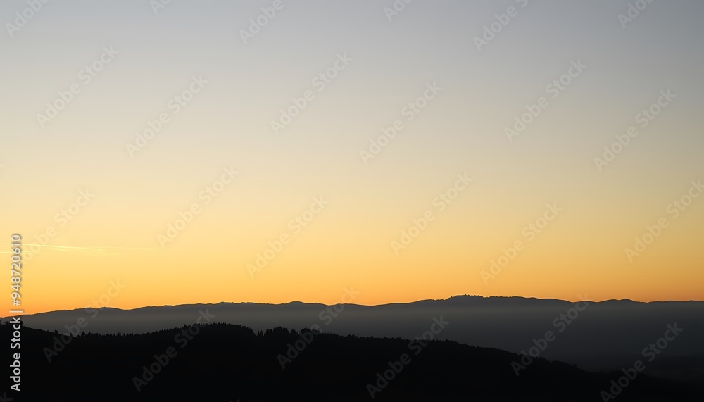 A hazy sunset over a silhouette of distant mountains. A hazy sunset over a silhouette of distant mountains.