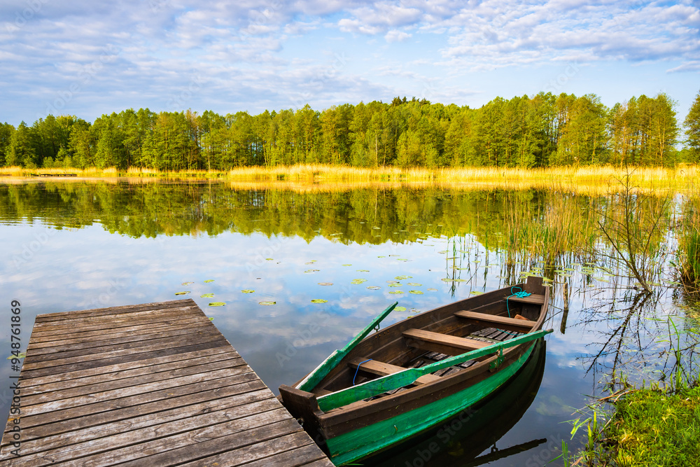 Wooden pier and fishing boat on shore of beautiful lake at sunrise, Suwalski Landscape Park, Podlasie, Poland Wooden pier and fishing boat on shore of beautiful lake at sunrise, Suwalski Landscape Park, Podlasie, Poland