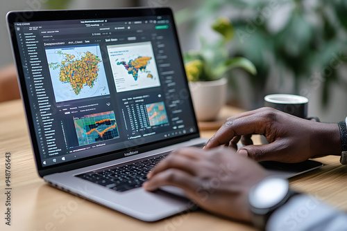A man is working on his laptop, which displays a geographic map with various regions