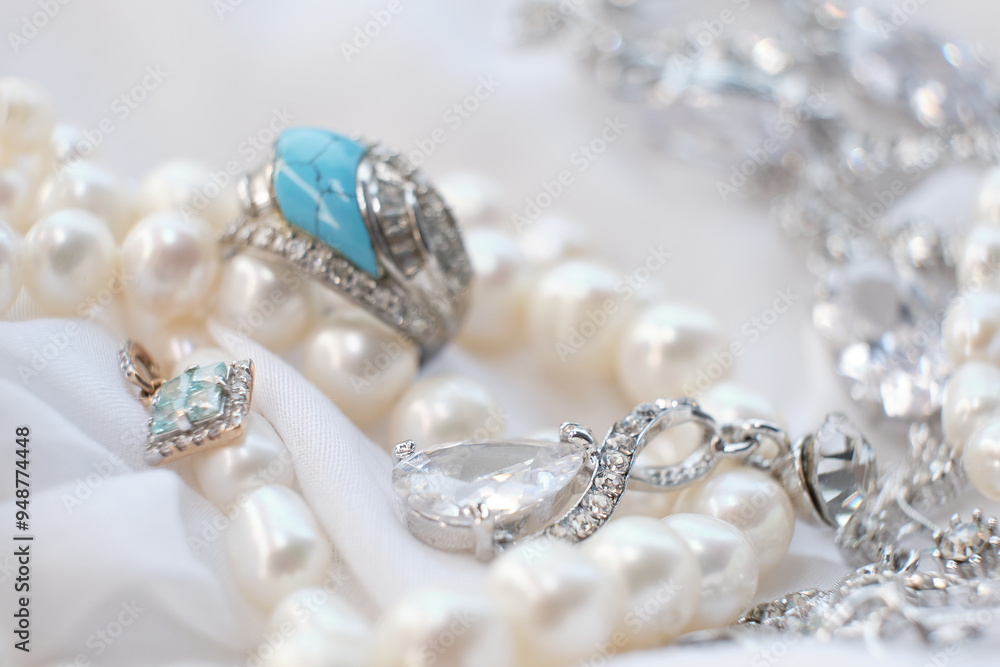 Jewelry featuring pearls, silver, and a striking blue gemstone is displayed on white fabric. The photo highlights the exquisite details and elegance of each piece, ideal for showcasing high-end Jewelry featuring pearls, silver, and a striking blue gemstone is displayed on white fabric. The photo highlights the exquisite details and elegance of each piece, ideal for showcasing high-end