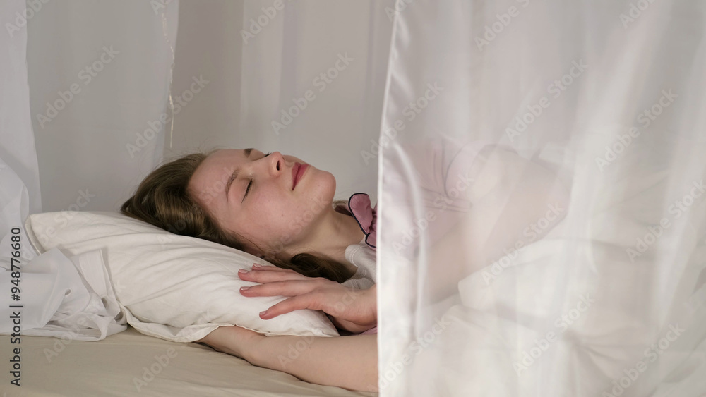 Sleeping peacefully, a woman in pink pajamas rests her head on a white pillow, enveloped by soft curtains. This photo captures the essence of calm and relaxation during sleep. Sleeping peacefully, a woman in pink pajamas rests her head on a white pillow, enveloped by soft curtains. This photo captures the essence of calm and relaxation during sleep.