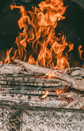 Tree branches burned into coals. Big flame in front of a barbecue. 