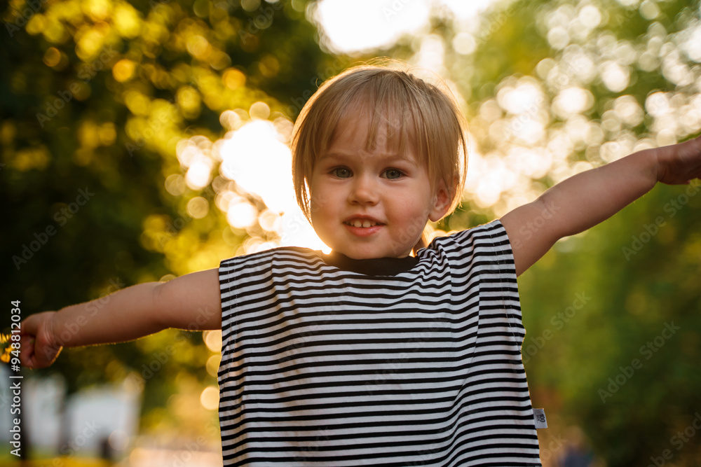 Cute Caucasian toddler child 2-years-old girl walks in a green park at sunset in summer. The concept of a joyful childhood and active pastime. Cute Caucasian toddler child 2-years-old girl walks in a green park at sunset in summer. The concept of a joyful childhood and active pastime.