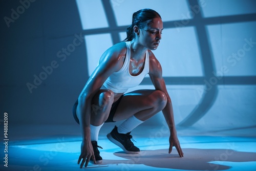 The Athlete's Focus: A powerful image of a determined female athlete in a dynamic pose, drenched in sweat under a dramatic blue light, exudes strength, resilience, and the unwavering pursuit of excell photo