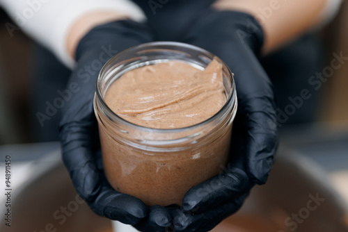 Baker confectioner fresh urbech paste of nuts pours into glass jars, top view photo