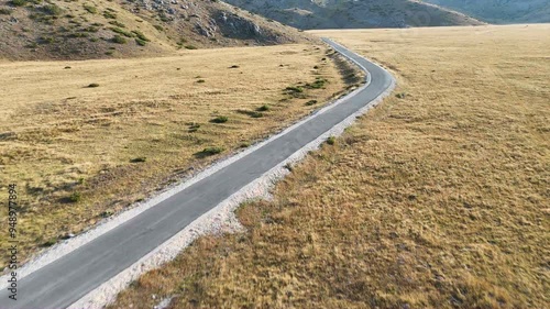 Open road in the high desert. Road through landscape. Road travel concept. Scenic view on the gravel road with stones and vegetation on roadsides