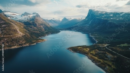   An aerial shot of a vast body of water encircled by snow-capped mountaintops, with a close-up bird's perspective of water in the foreground