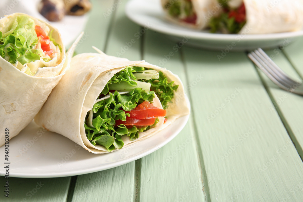 Plate of tasty lavash rolls with tomatoes and greens on green wooden background Plate of tasty lavash rolls with tomatoes and greens on green wooden background