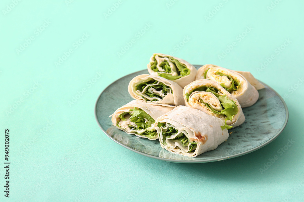 Plate of tasty lavash rolls with egg and greens on turquoise background Plate of tasty lavash rolls with egg and greens on turquoise background