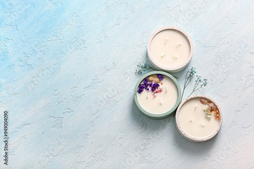 Holders with candles and flowers on blue background