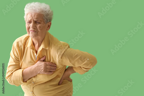 Elderly woman having heart attack on green background