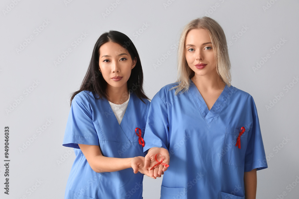 Female doctors with red ribbons on grey background. World AIDS Day concept Female doctors with red ribbons on grey background. World AIDS Day concept