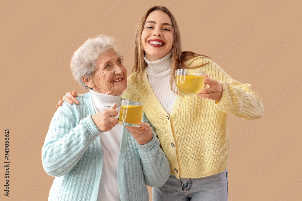 Young woman and her grandmother with glass cups of lemon tea on beige background Young woman and her grandmother with glass cups of lemon tea on beige background