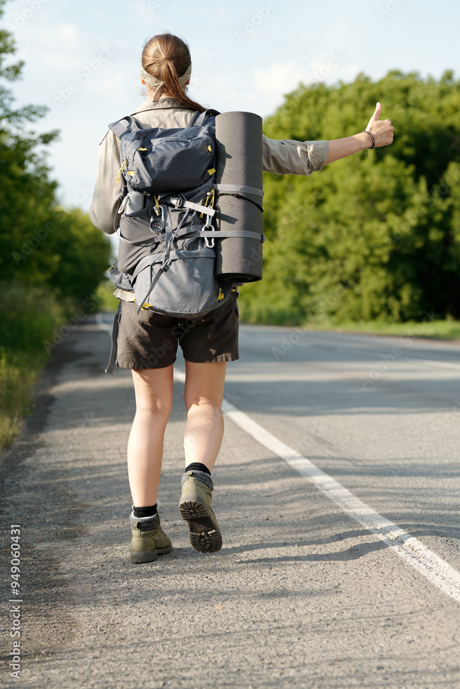 Back view of active girl in casualwear catching car or other vehicle on highway while traveling alone in non urban environment