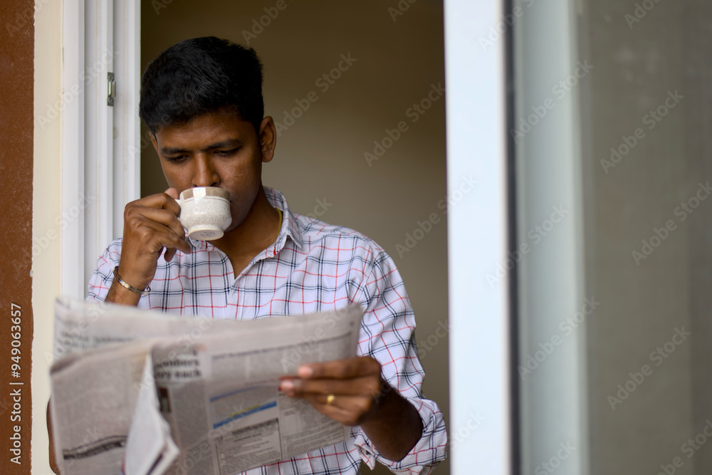 Fototapeta premium Man enjoying his morning coffee while reading the newspaper at home during a quiet morning
