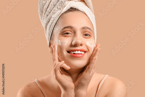 Young woman in towel applyi...