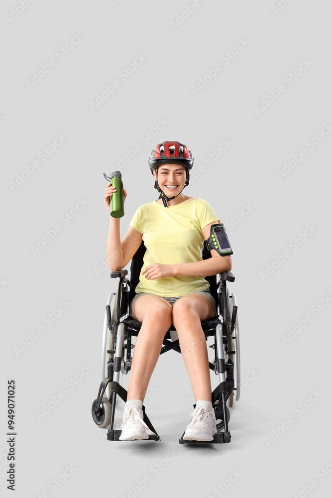 Female cyclist in wheelchair with water bottle on light background Female cyclist in wheelchair with water bottle on light background