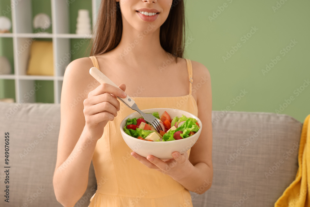 Young woman with bowl of vegetable salad on sofa in living room Young woman with bowl of vegetable salad on sofa in living room