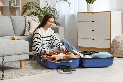 Young woman packing suitcas...